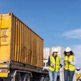 Two female workers in safety vests and hard hats at a worksite